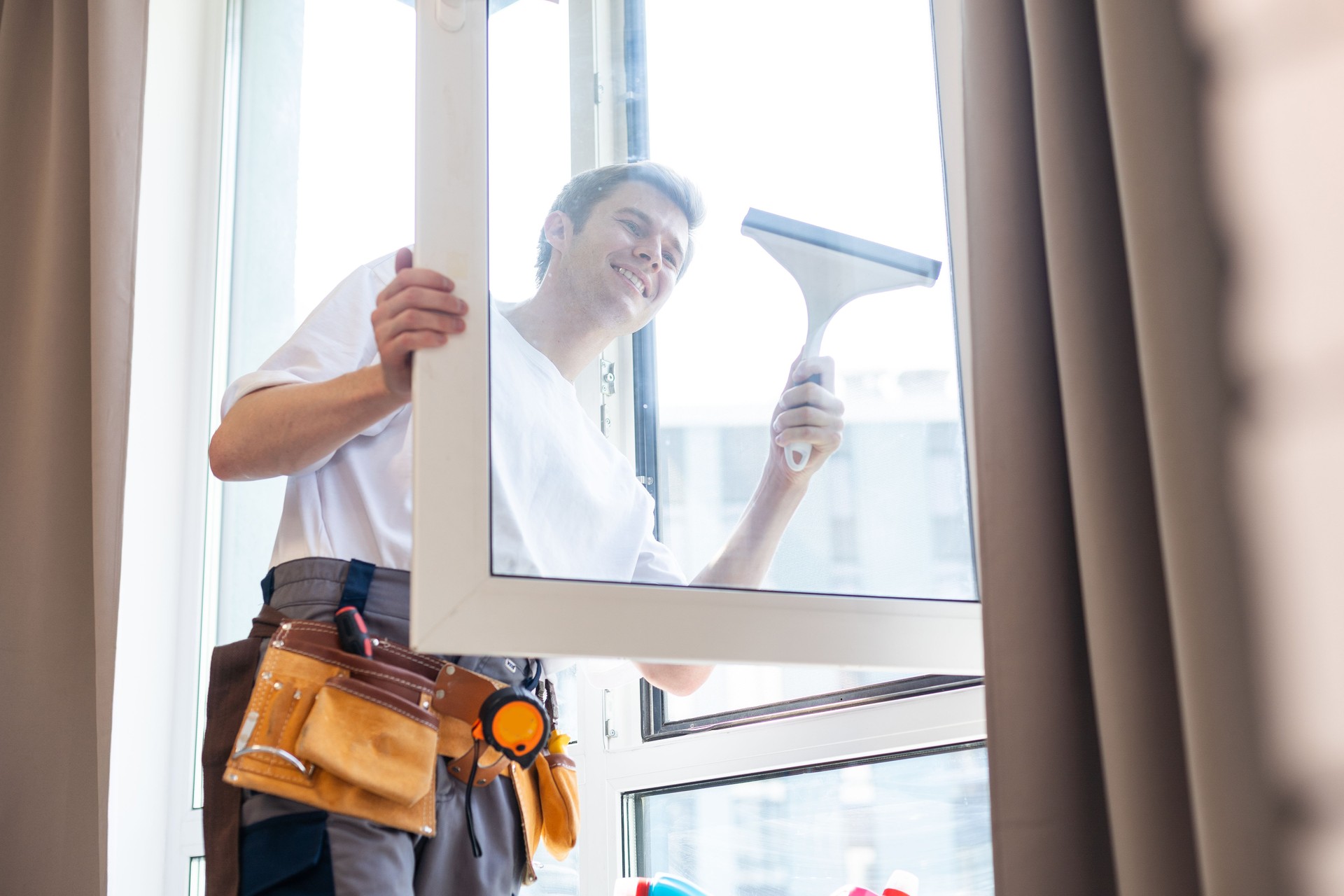 Young man washing window in office