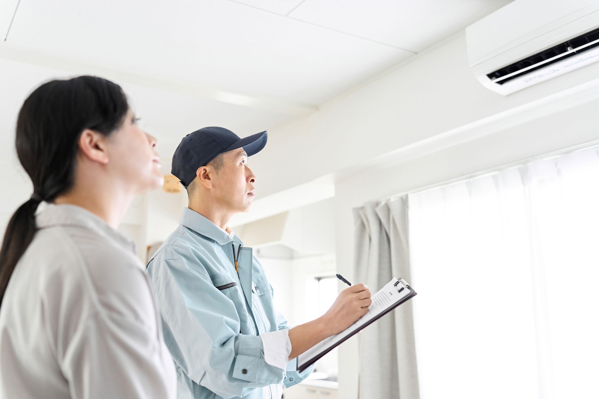 Asian worker inspecting air conditioner